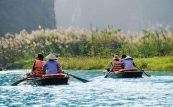 People enjoying paddle boating on a calm lake near Lahore with trees and sky in the background.