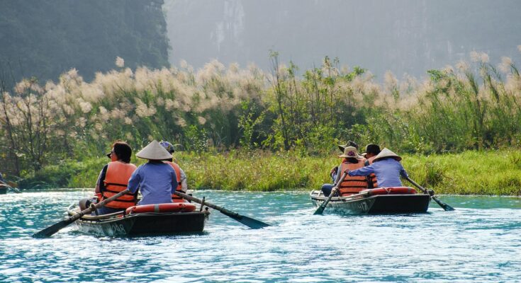 People enjoying paddle boating on a calm lake near Lahore with trees and sky in the background.
